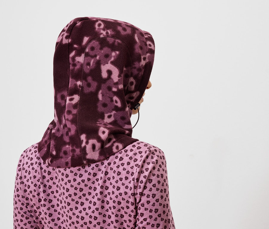 Vue arrière d'une femme portant un hijab floral violet et une chemise violette à motif de cœur.