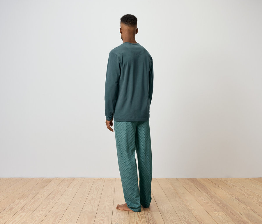 Un homme, vu de dos, porte un pyjama vert.