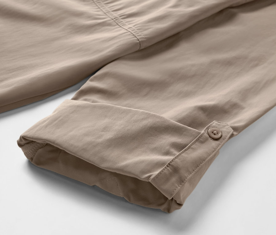 Gros plan sur une chemise d’extérieur beige avec protection anti-moustiques et manches retroussées.