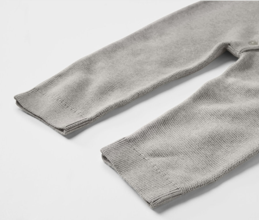 Détail d'une combinaison en maille grise pour bébé.