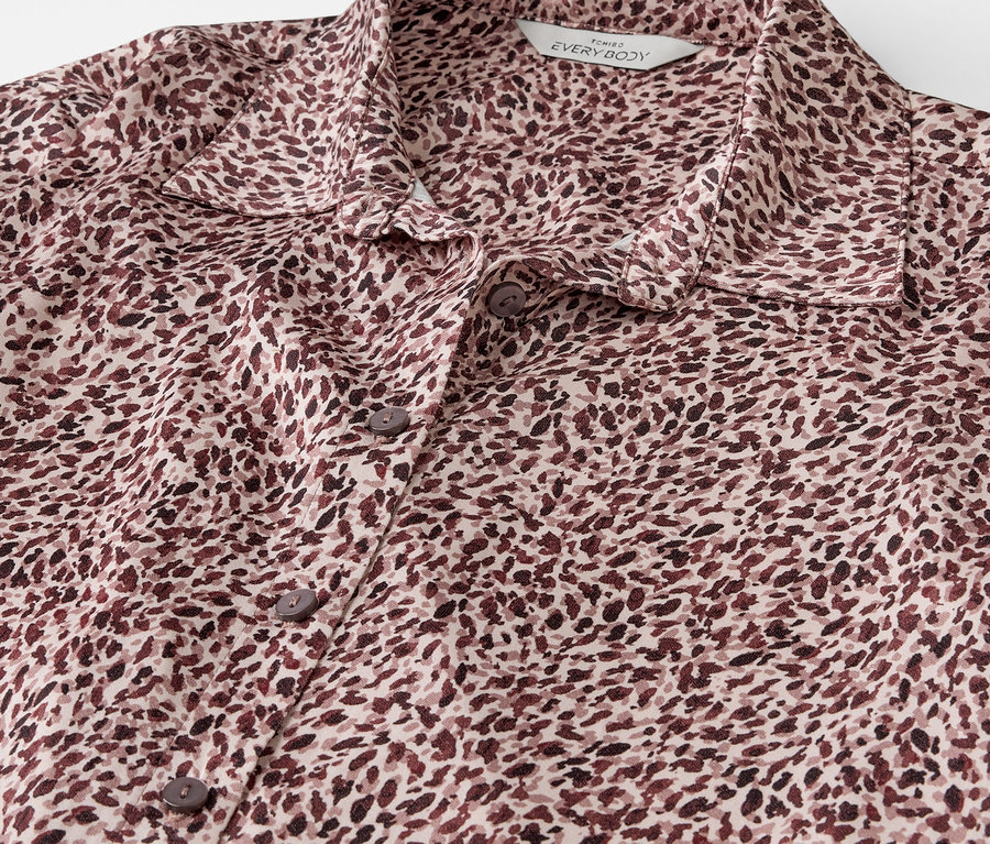 Gros plan d'une chemise marron et crème avec des boutons et un motif.