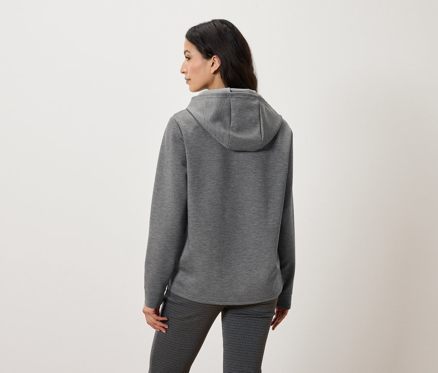 Vue arrière d'une femme portant un sweat à capuche gris et un pantalon à motifs.