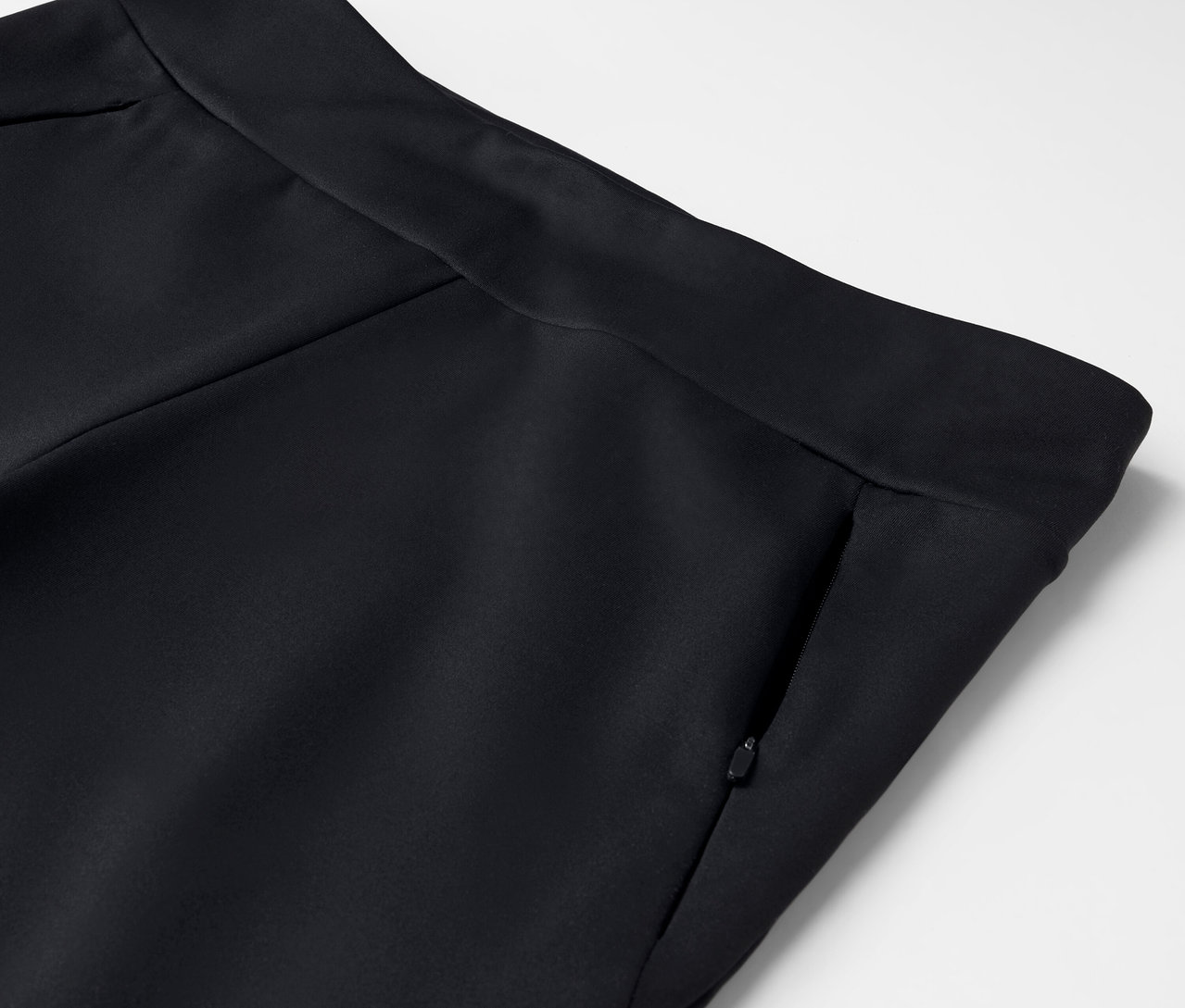 Détail d'un pantalon noir avec une poche zippée.