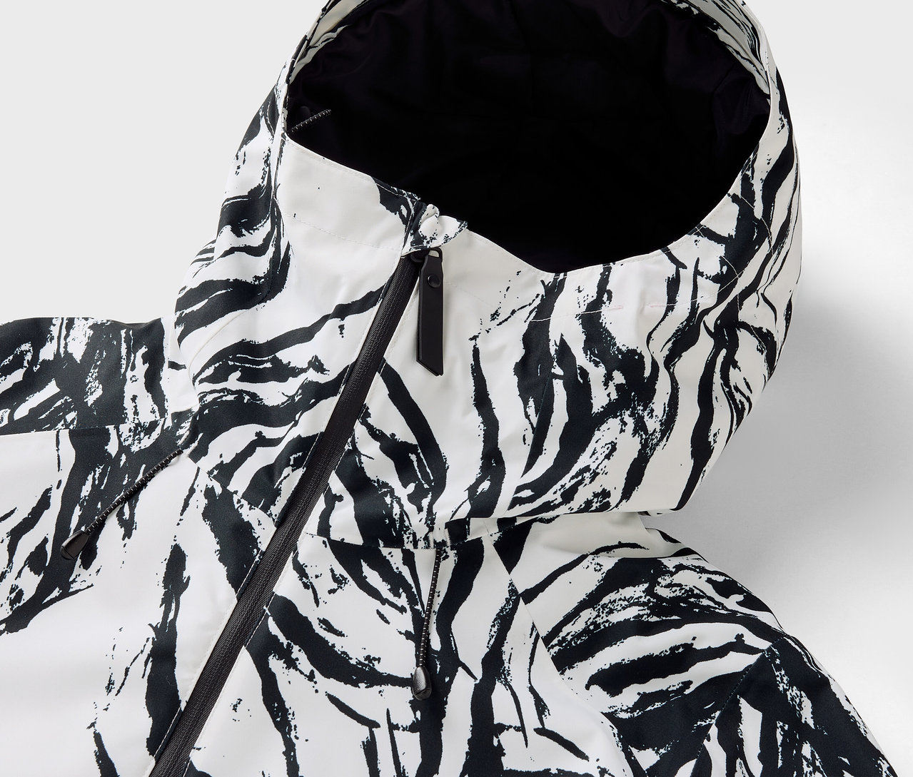 Gros plan sur la capuche d'une veste à motif zébré avec une fermeture éclair noire.