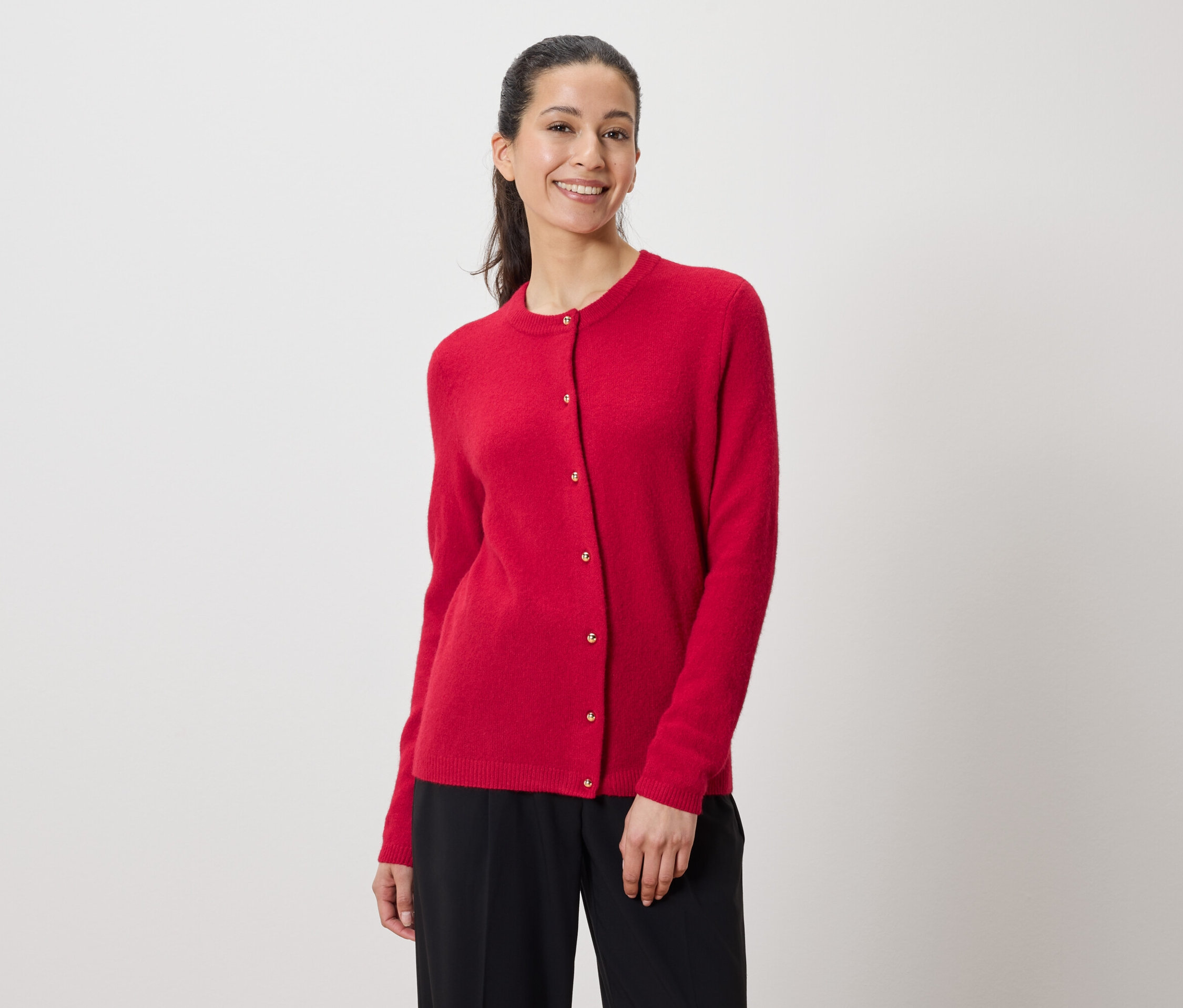 Une femme porte un cardigan rouge et un pantalon noir.