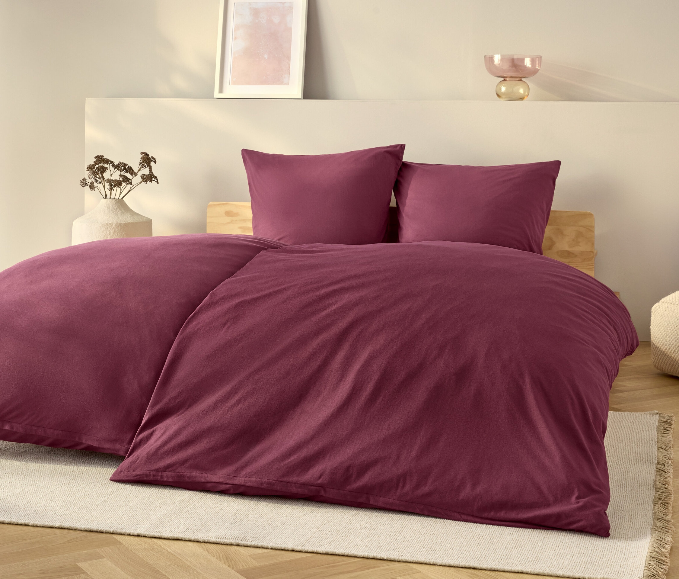 Une parure de lit violette sur un lit avec un tapis blanc.