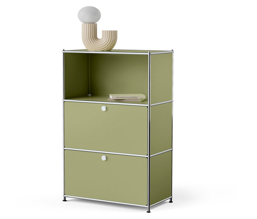 Armoire verte avec deux tiroirs et une étagère supérieure ouverte avec un livre et une lampe décorative.