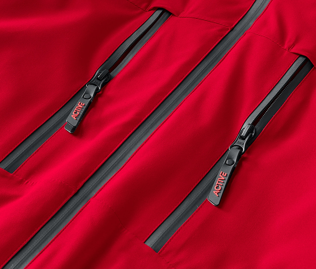Gros plan sur une veste rouge avec deux fermetures éclair grises portant l'inscription ACTIVE.