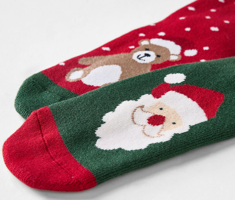 Gros plan de chaussettes de Noël rouges et vertes avec un ours et le Père Noël.