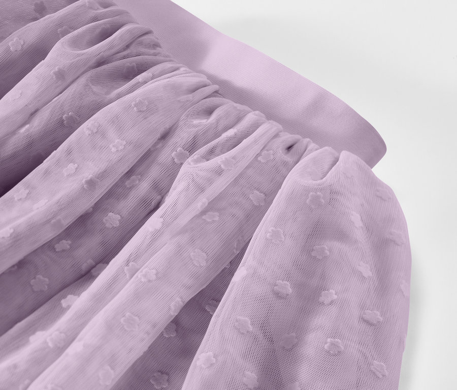 Gros plan sur un tissu de tulle lavande froncé avec un motif à pois.