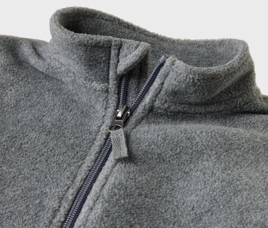 Gros plan sur une combinaison en polaire grise pour bébé avec une fermeture éclair ouverte.