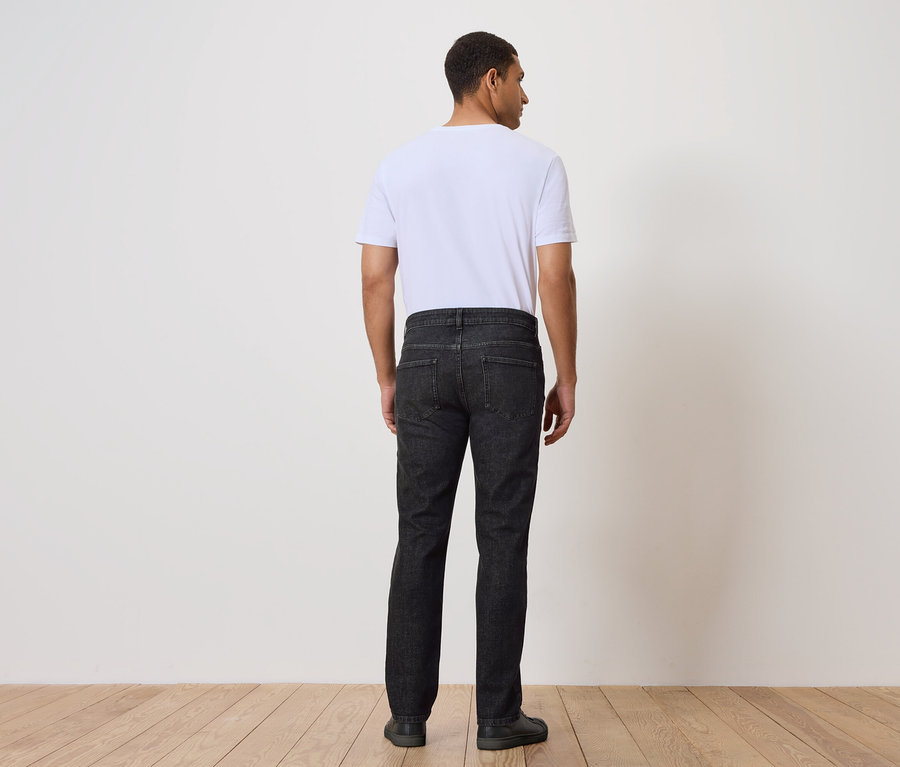 Un homme, dos à la caméra, porte un jean et un t-shirt.