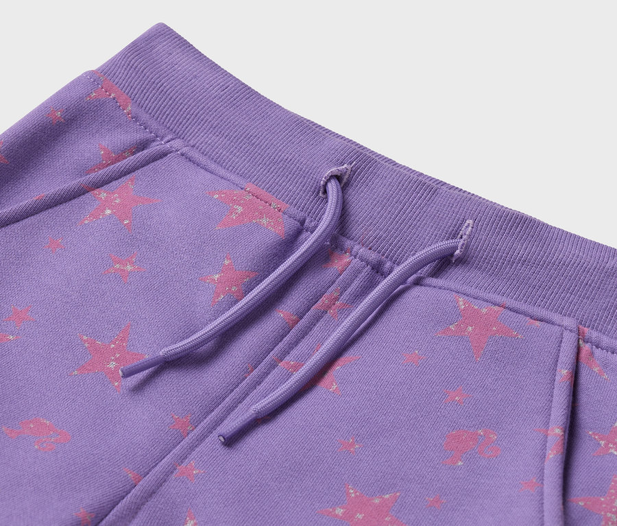 Gros plan sur un pantalon de jogging violet avec un motif d'étoiles roses et un cordon de serrage.