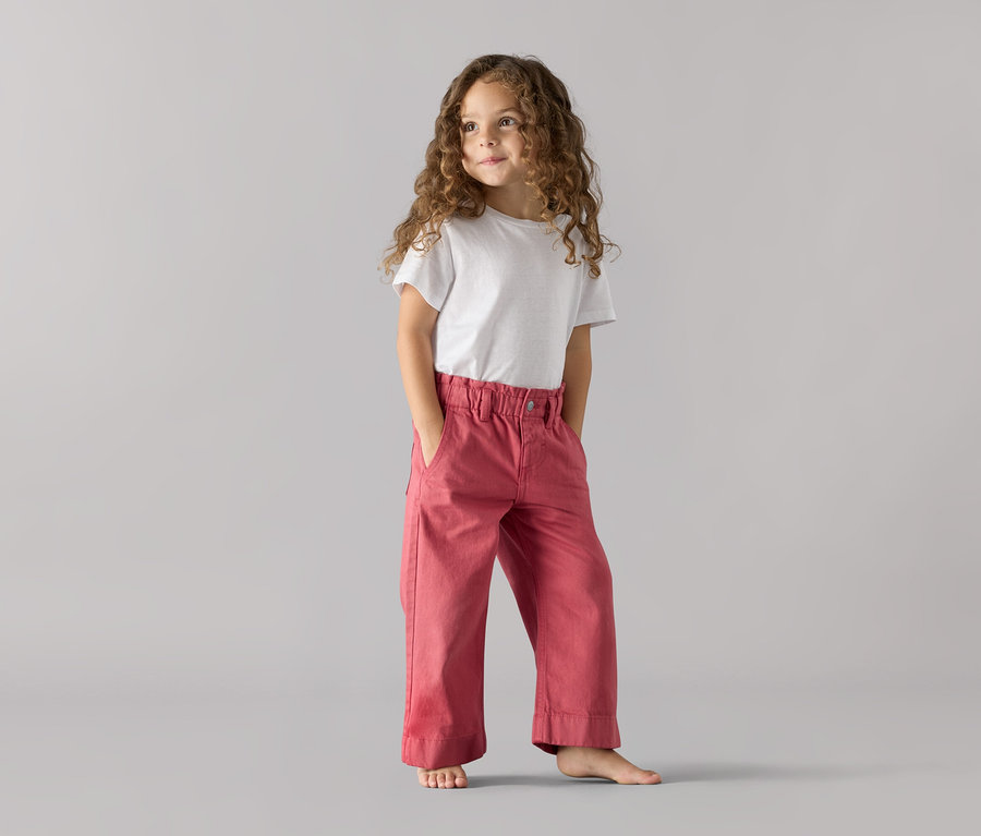 Fillette debout, les mains dans les poches d'un jeans pour enfants coupe « Greta ».