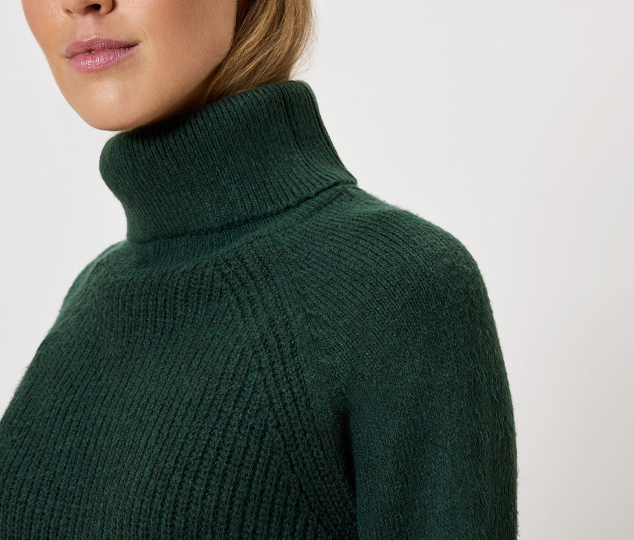 Gros plan sur un pull à col roulé vert foncé pour femme.