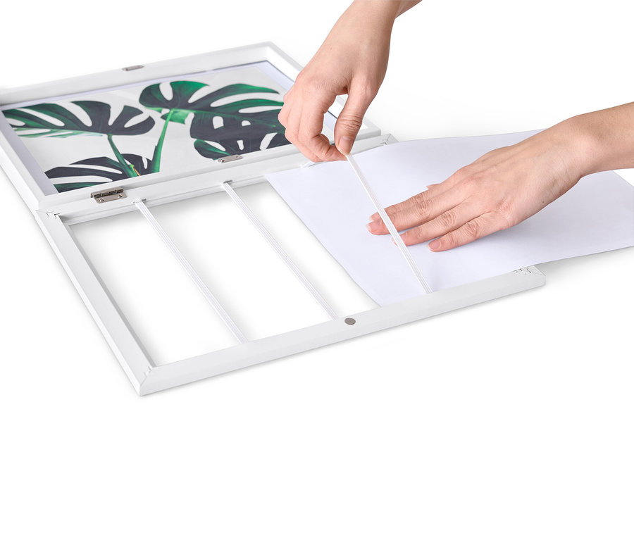 Des mains insèrent une feuille de papier blanche dans un cadre repliable.