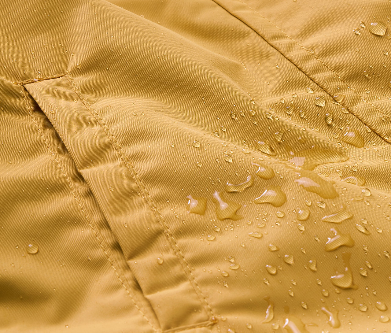 Gros plan sur une combinaison de pluie pour enfant avec une poche et des gouttes d'eau.