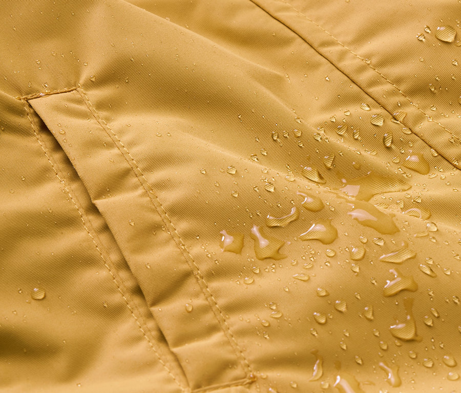 Gros plan sur une combinaison de pluie pour enfant avec une poche et des gouttes d'eau.