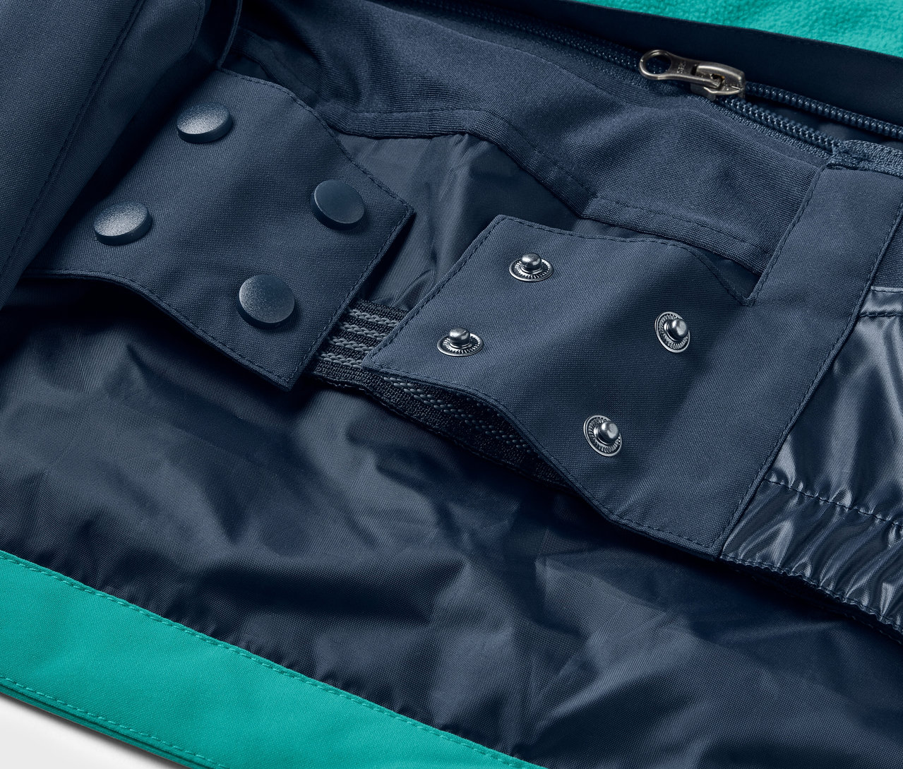 Détail d'une veste avec boutons-pression bleus et fermeture éclair.