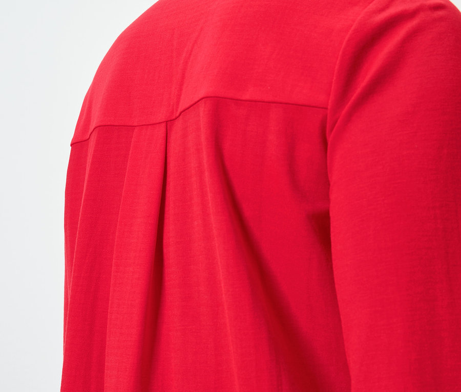 Gros plan sur le dos d'une chemise rouge à manches longues avec des plis
