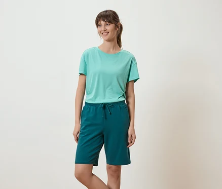 Femme portant un t-shirt vert clair et un short vert sur fond blanc.