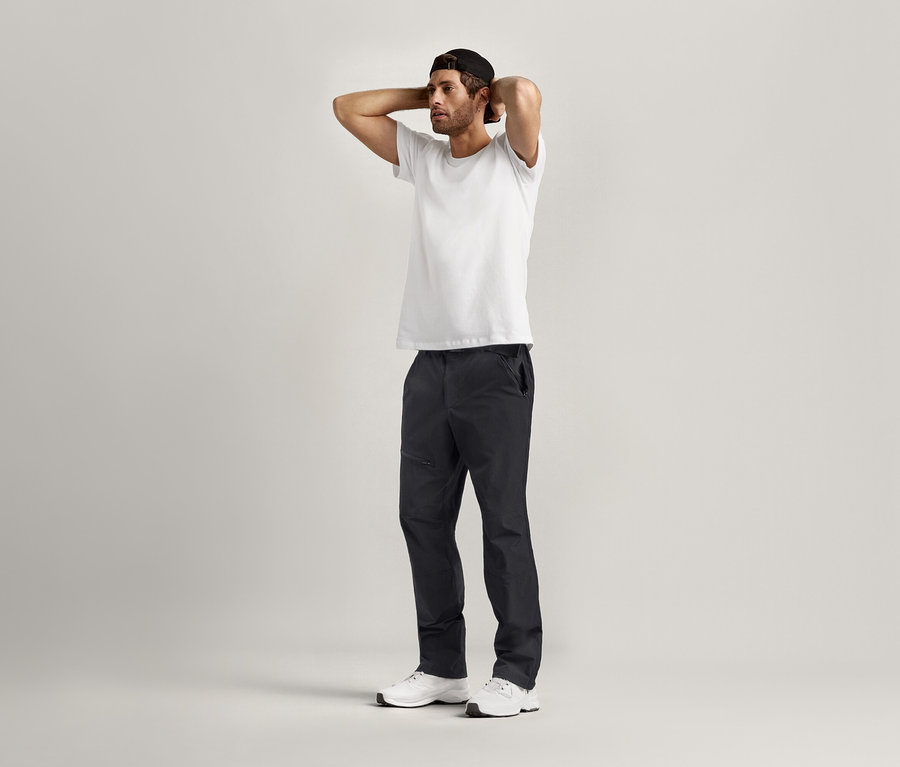 Un homme pose les mains derrière la tête et porte 2 T-shirts à encolure ronde blancs.