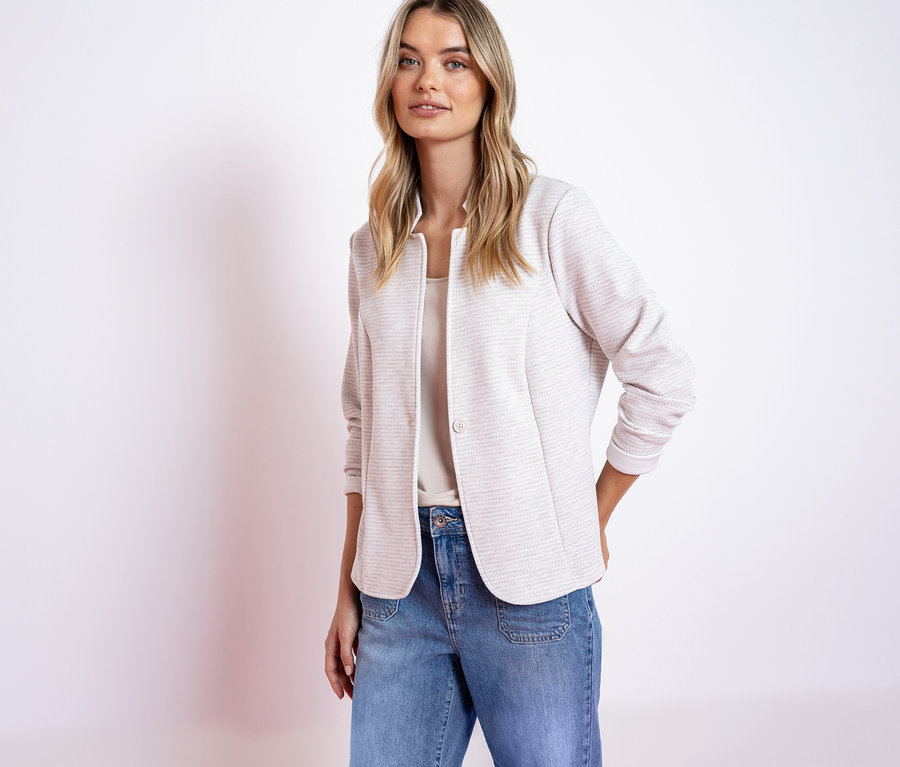 Femme portant un blazer en jersey Street One rose et un jean, les mains dans les poches.