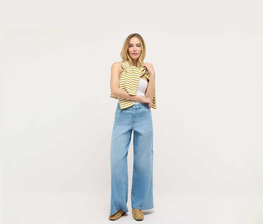 Une femme se tient devant un fond blanc et porte un jean Angels Denim « Liva » Cargo Wide Leg.