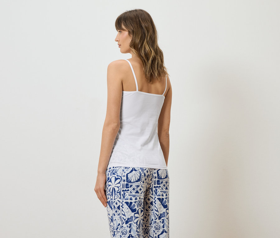 Femme vue de dos portant un haut blanc et un pantalon à motifs bleus et blancs.