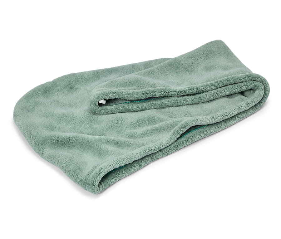 Une serviette pliée vert clair est posée sur un fond blanc.