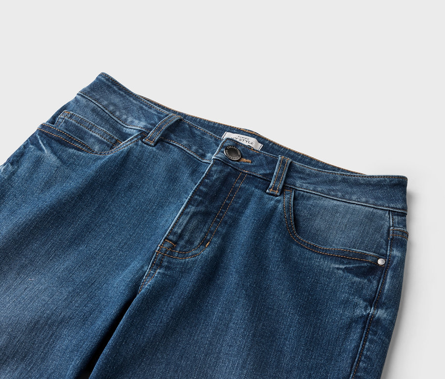 Gros plan d'un jean en denim foncé avec des poches et un bouton.