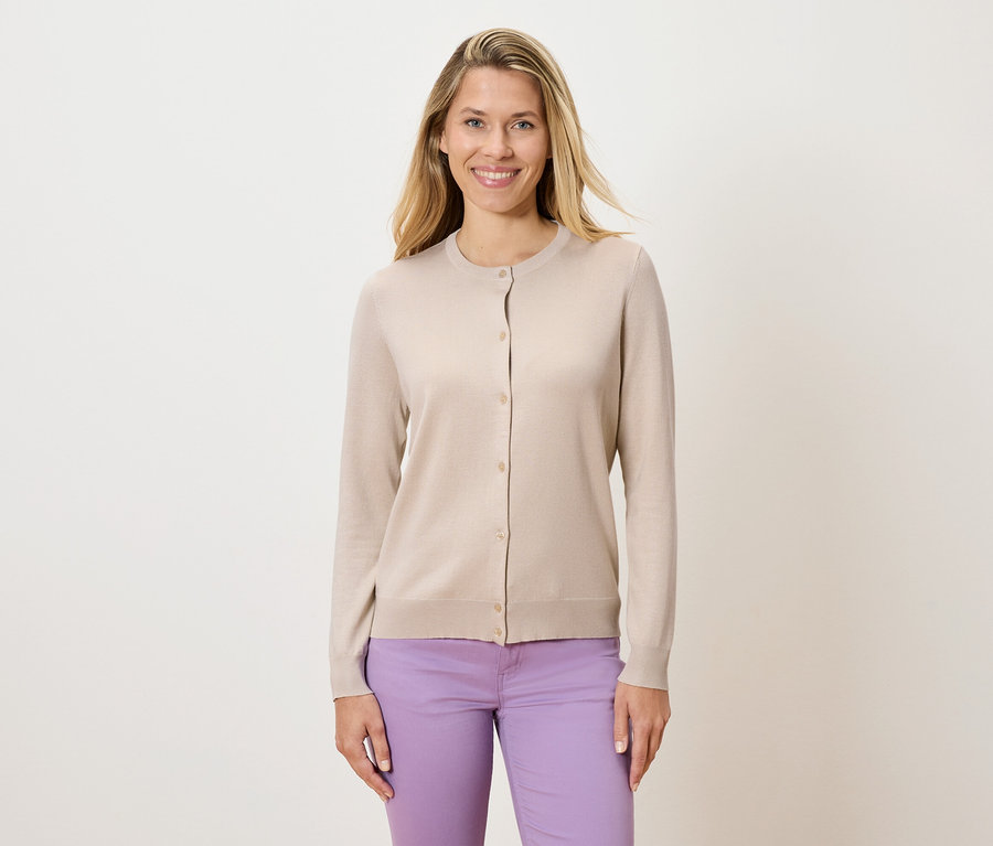 Femme portant un cardigan beige et un pantalon violet.