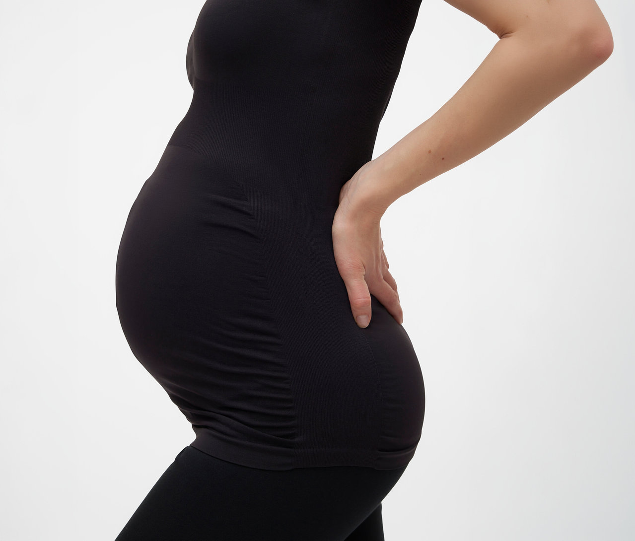 Femme enceinte portant un débardeur noir MAMALICIOUS « MLHEAL » taille unique et un legging, main sur le dos.