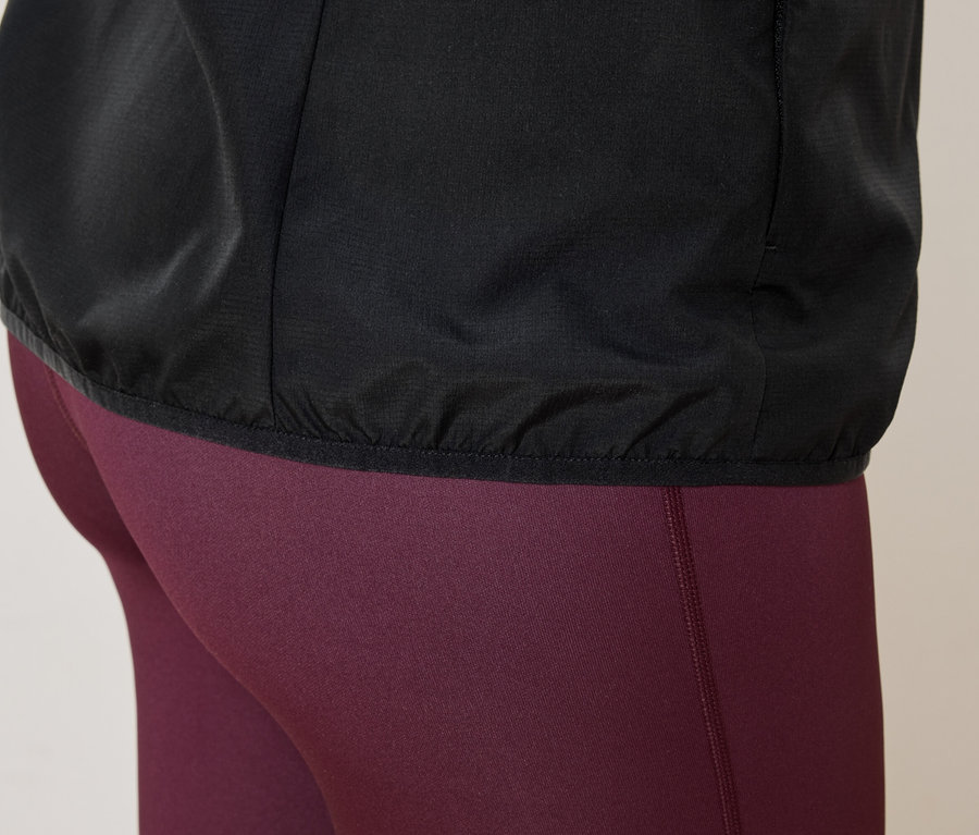Gros plan d'une personne portant une veste noire et un legging bordeaux.