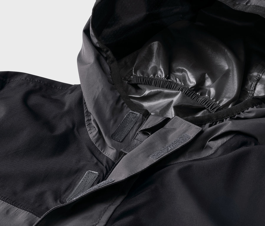 Gros plan d'une veste noire à capuche fixée par des scratchs.