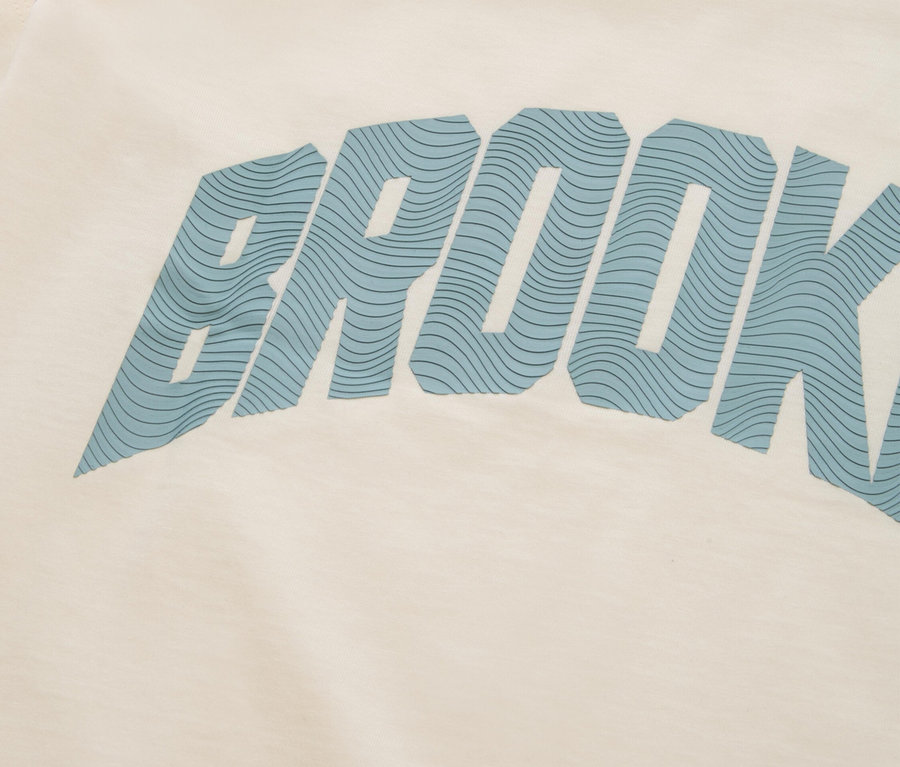 Gros plan sur un t-shirt crème avec l'inscription bleue « BROOKLYN ».