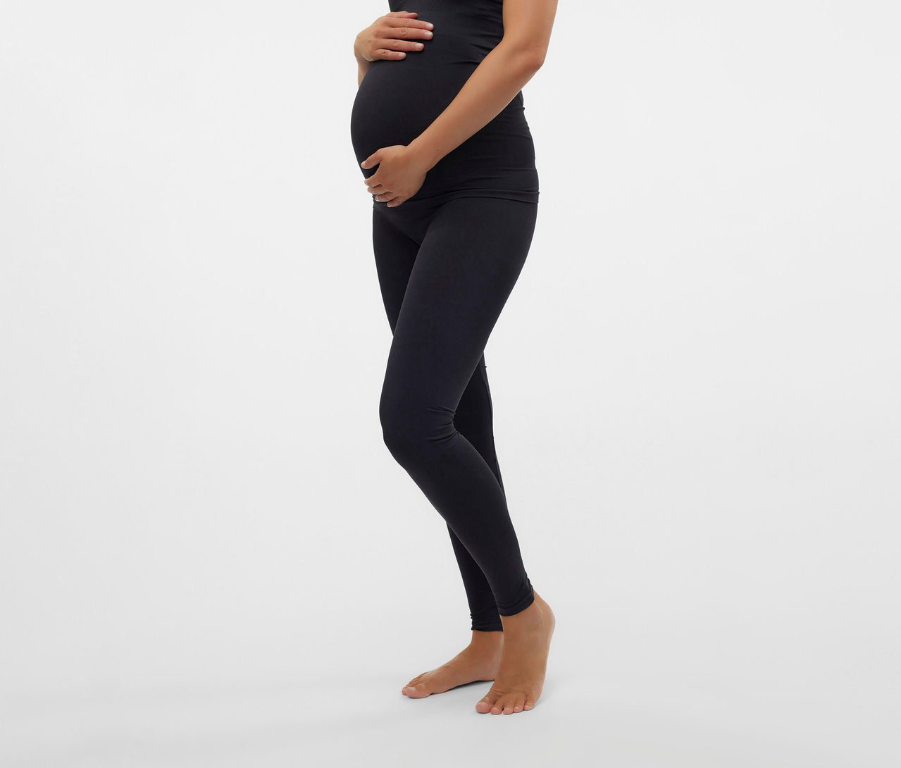 Femme enceinte tenant son ventre, portant un débardeur noir et un Skinny Leggings MAMALICIOUS «
MLTIA JEANNE
».