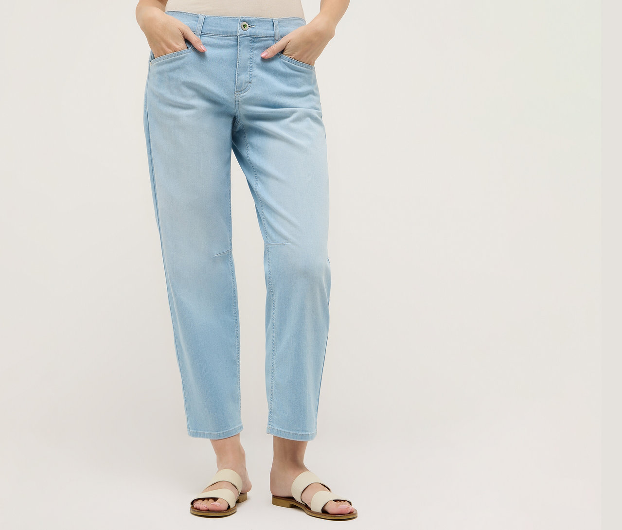 Femme portant un jean Angels Denim « Evy Cool » O-Shape bleu clair et des sandales. Ses mains sont dans ses poches.