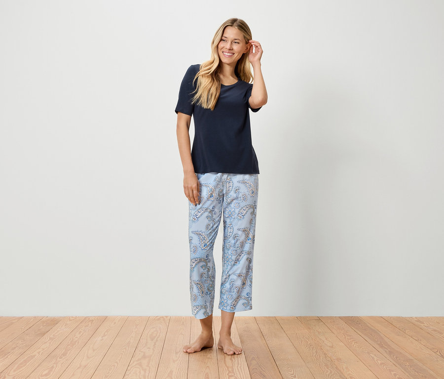 Femme blonde portant un t-shirt bleu et un pantalon bleu clair à motifs.