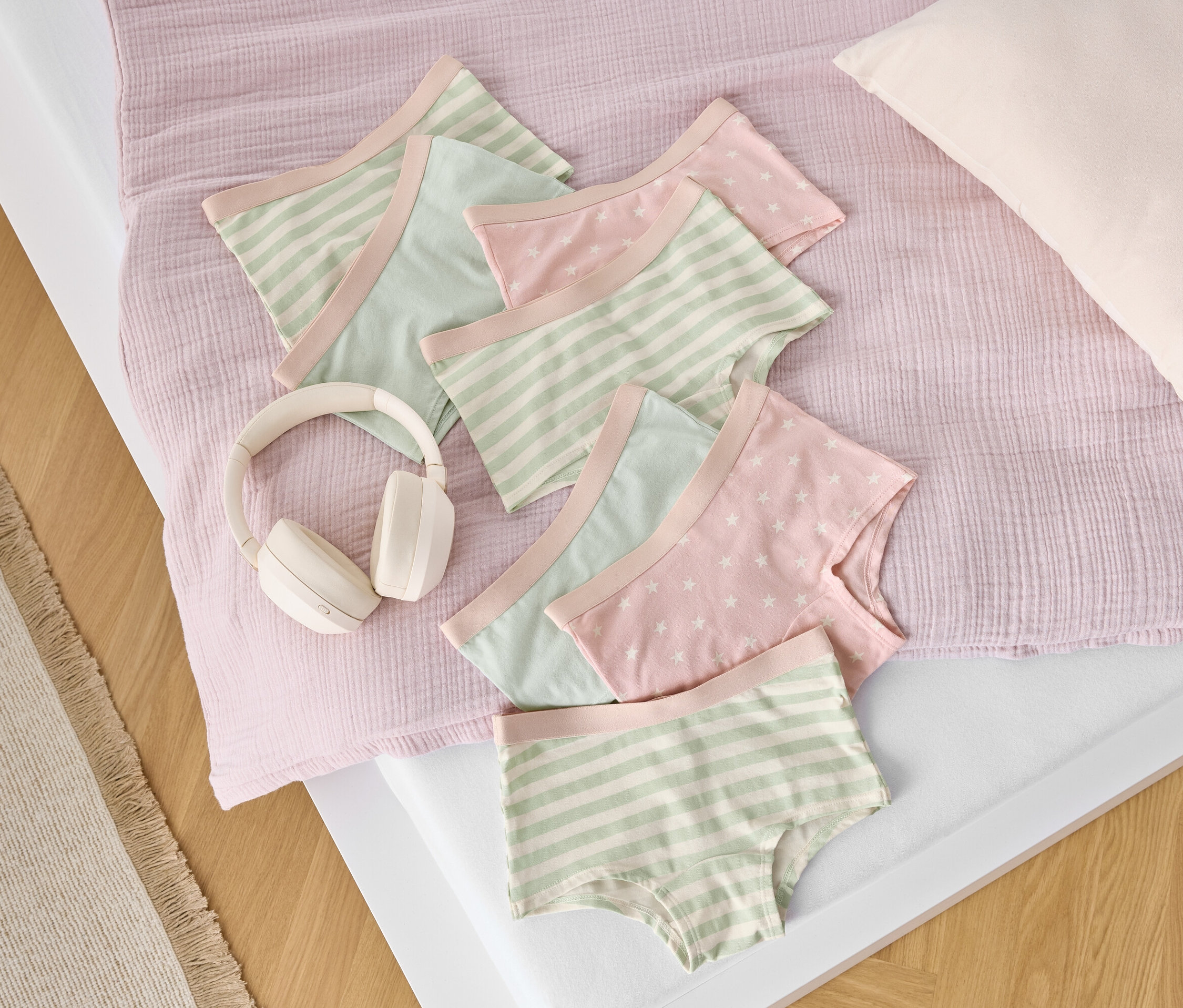 Sur un lit, des slips en coton à rayures et à étoiles sont posés à côté d'un casque blanc.