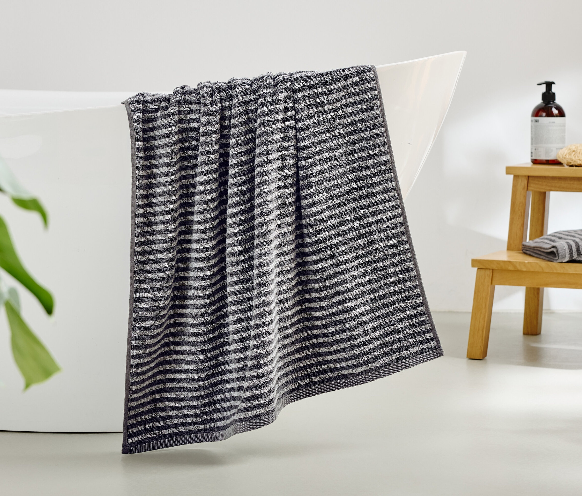 Une serviette rayée est suspendue au bord d'une baignoire.