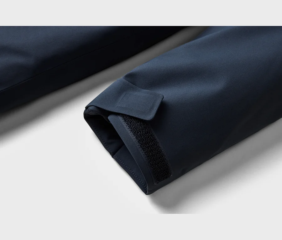 Gros plan d'une manche de veste bleu marine avec un poignet ajustable doté d'une fermeture auto-agrippante noire.