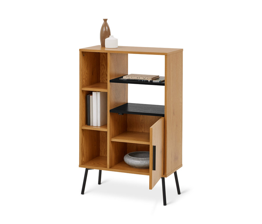 Une étagère en bois clair avec des pieds noirs et plusieurs compartiments. Elle comporte des étagères noires, un vase marron, un récipient blanc, trois livres blancs et des papiers. Un bol gris est visible à l'intérieur d'un compartiment à porte partiellement ouverte.