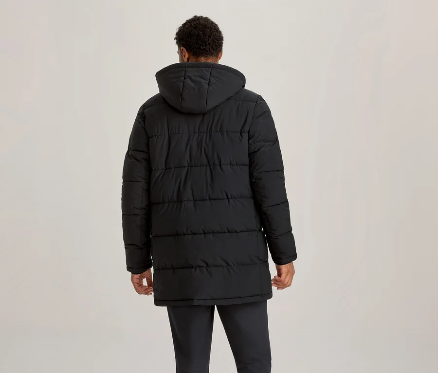 Personne de dos, portant une doudoune noire à capuche qui arrive à mi-cuisse.