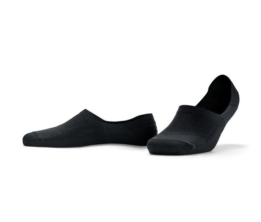 Deux paires de socquettes de sport noires sont posées sur le sol.