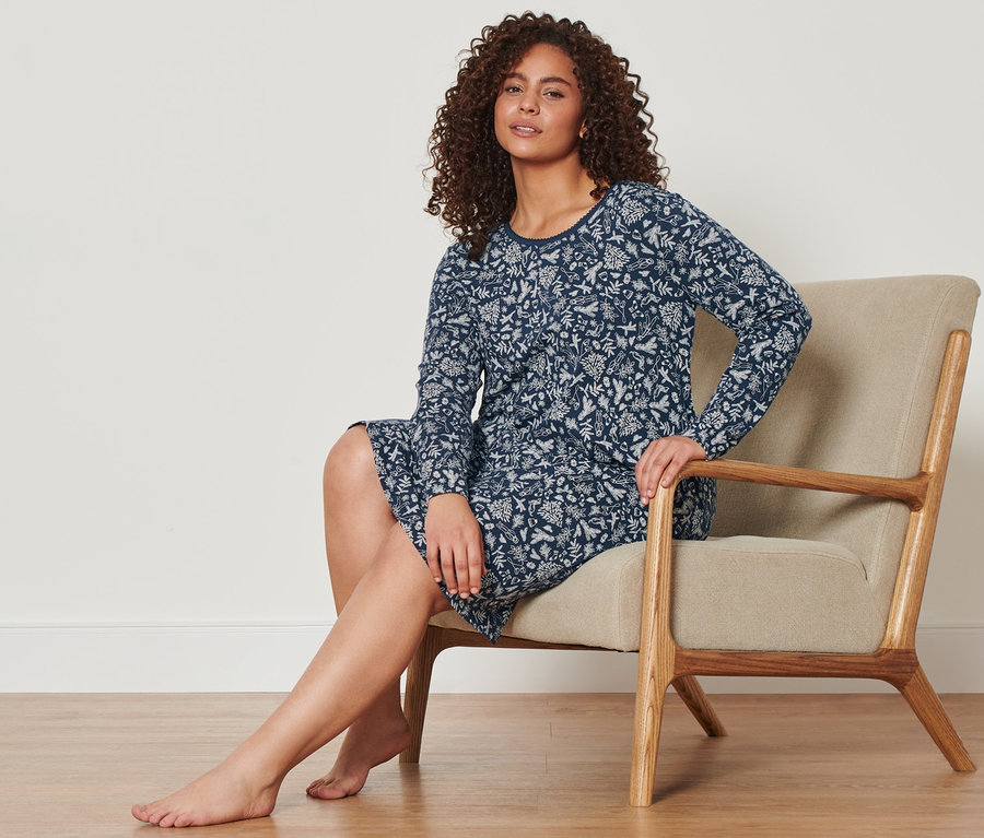 Une femme assise dans un fauteuil porte une chemise de nuit bleue.