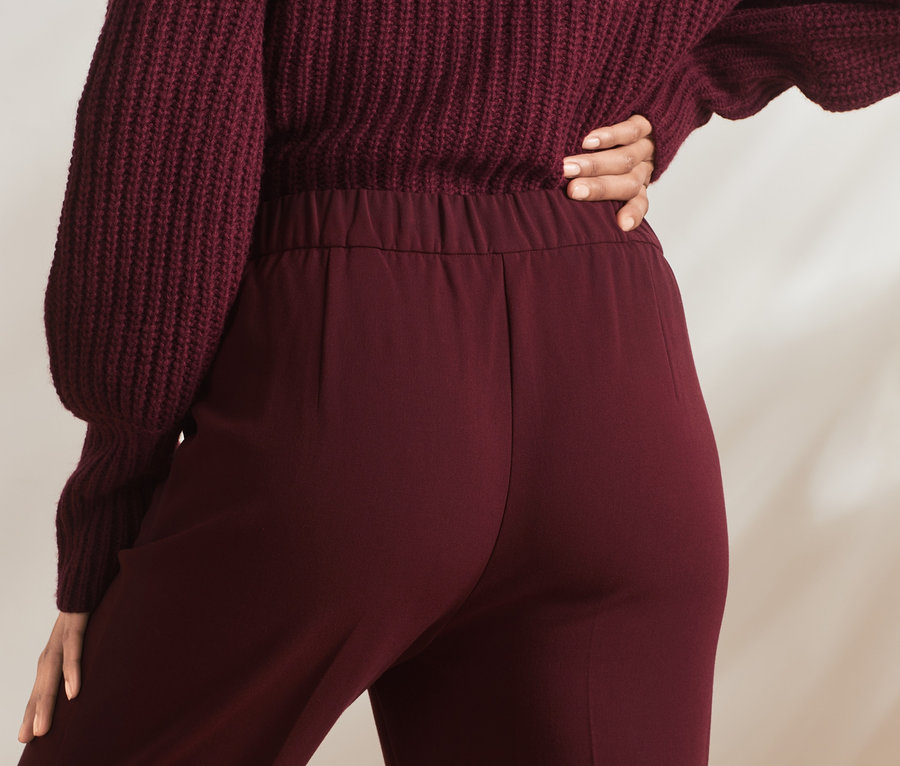 Une personne porte un pantalon en tissu et un pull.