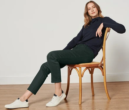 Femme assise sur une chaise portant un pantalon twill vert foncé avec ceinture confort.