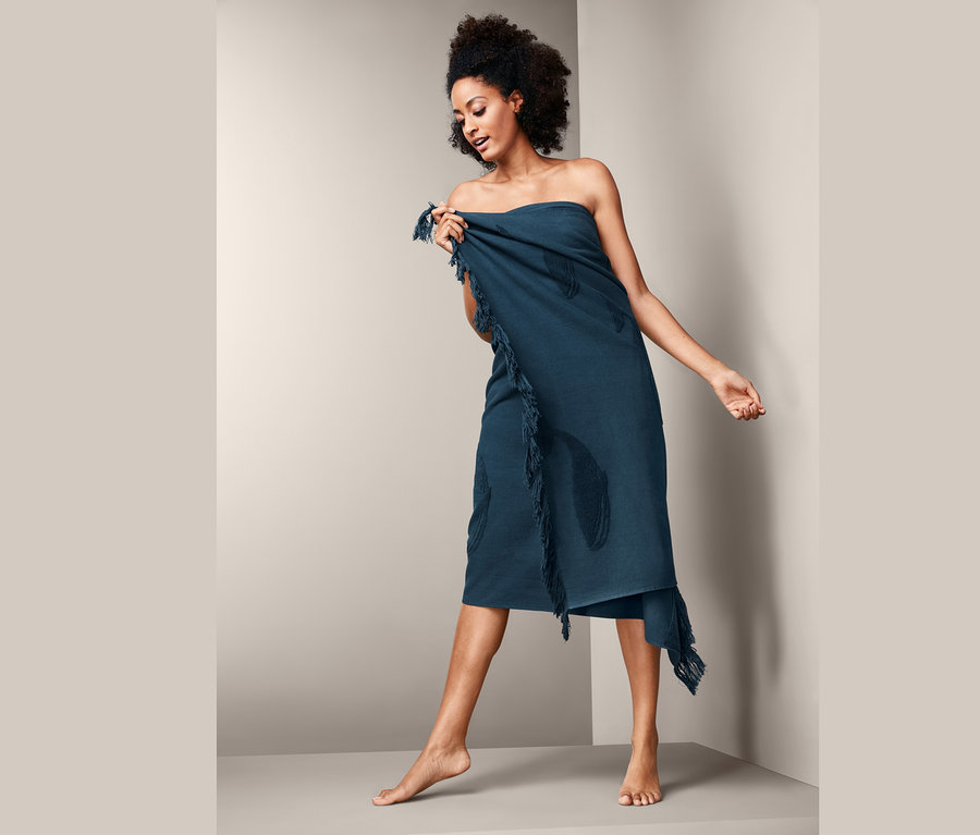 Femme enveloppée dans un linge de bain XL à franges.