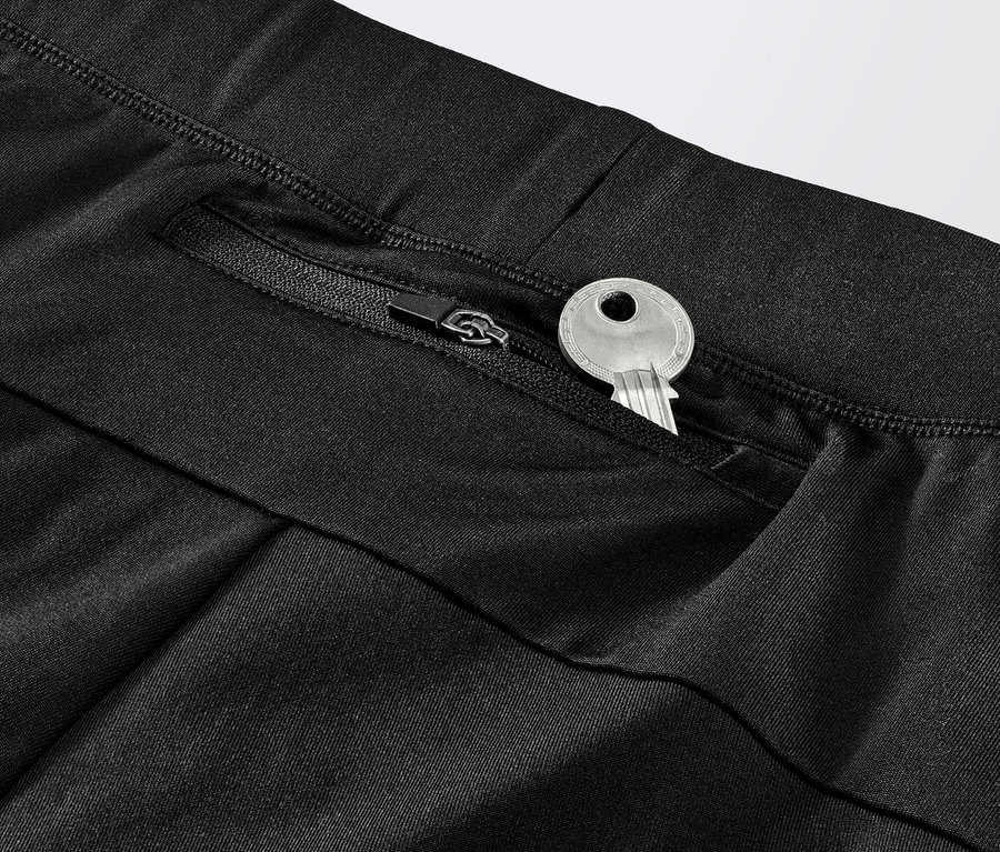 Gros plan sur un legging de course coupe-vent noir avec une clé dans la poche zippée.